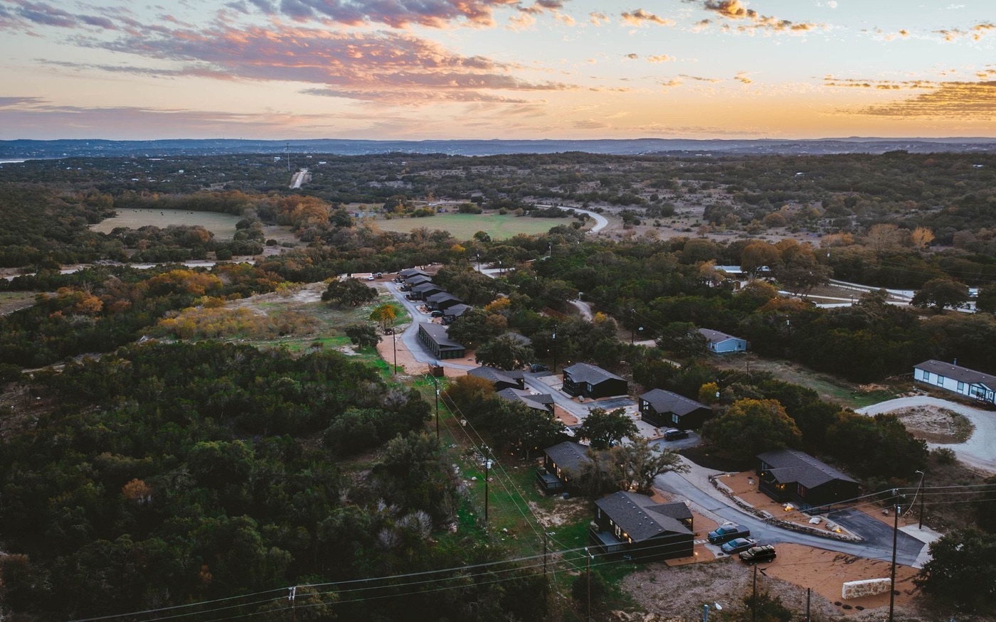 A cabin property at dusk, lights on across the whole site.